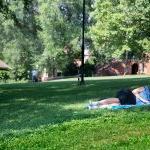 Student laying on the grass, studying on front campus